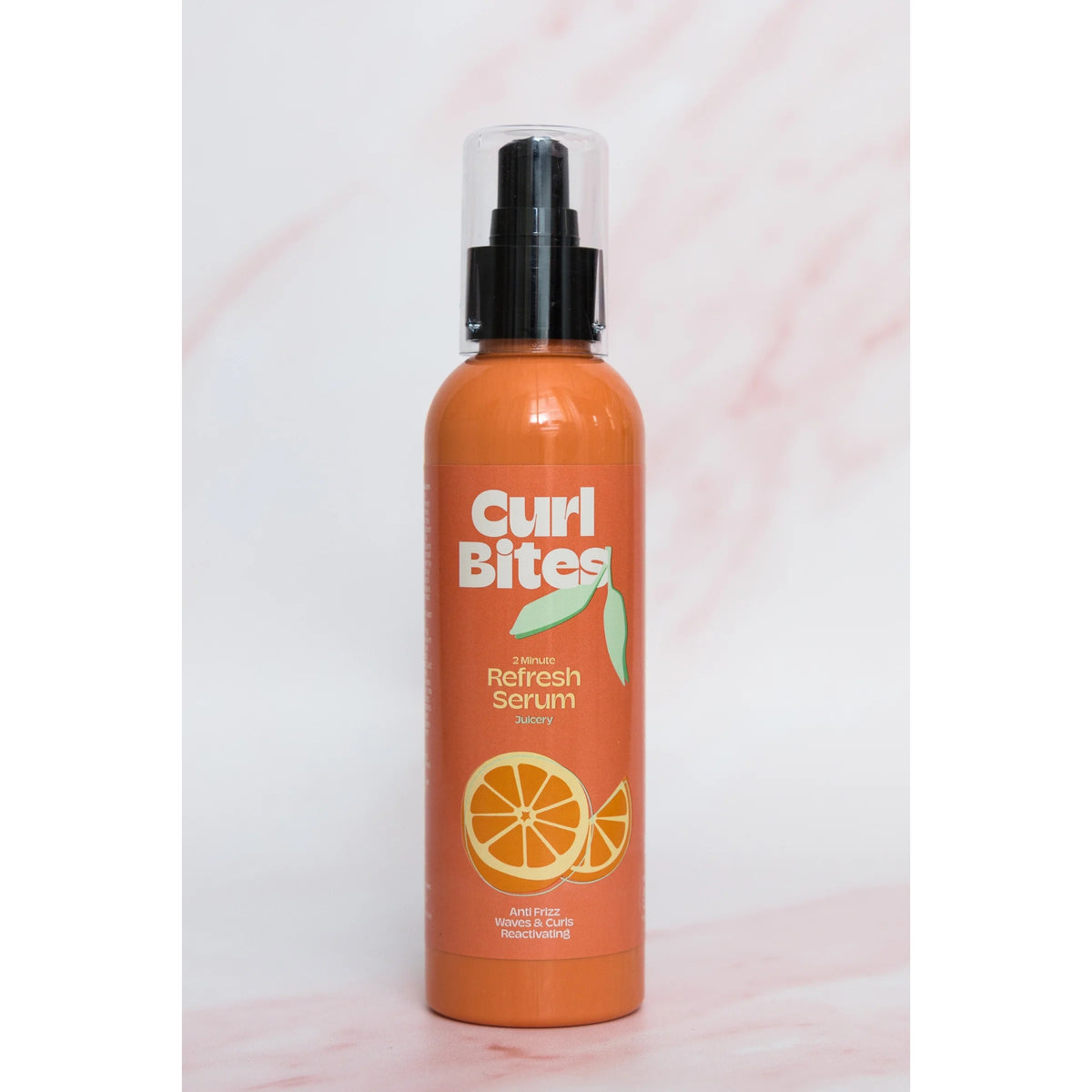 Curl Bites 2 Minute Refresh Serum, orange flaske med sort pumpe og appelsinmotiv på lys marmorbaggrund.