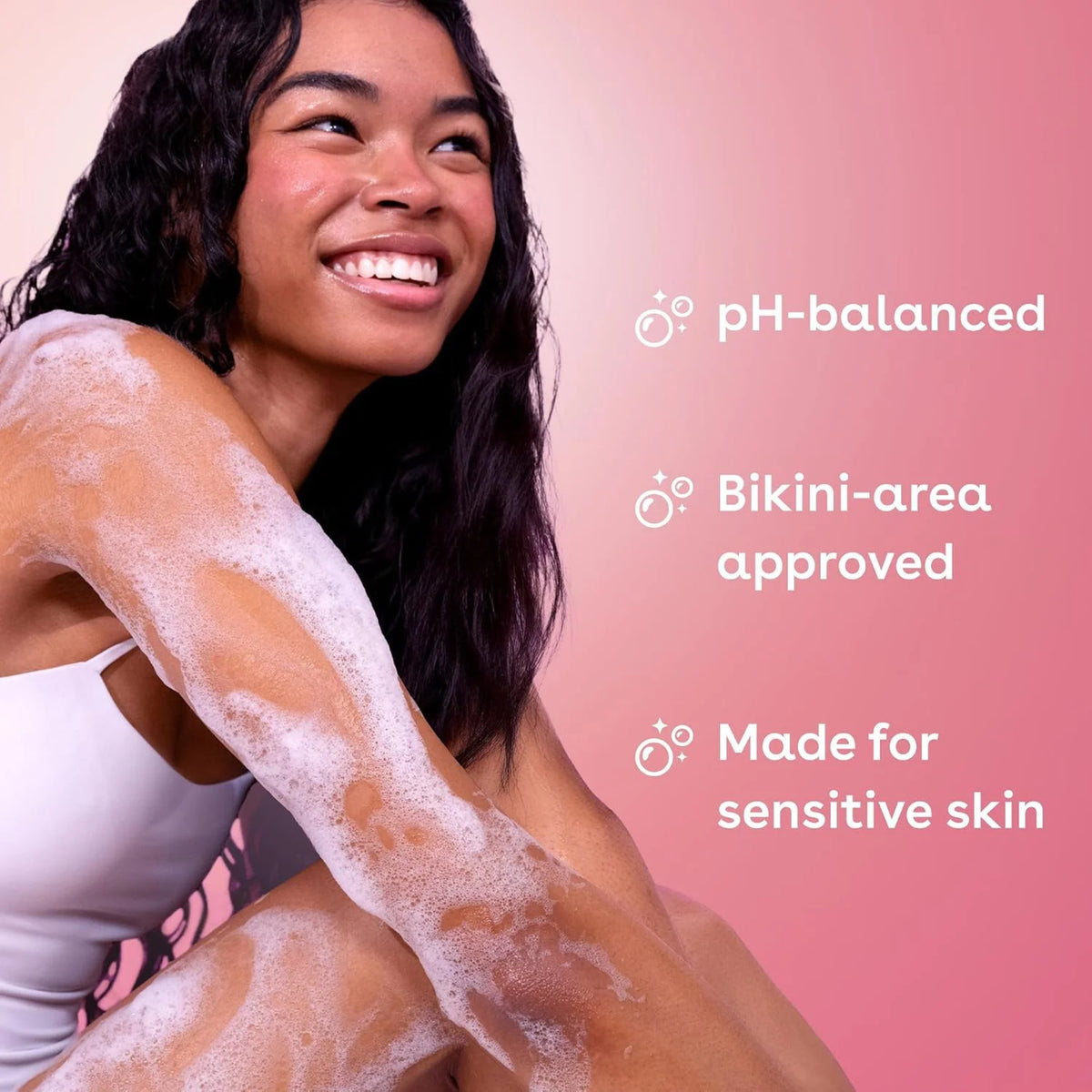 Smilende kvinde med sæbeskum på arm, pH-balanceret bikini-area sæbe til sensitiv hud.