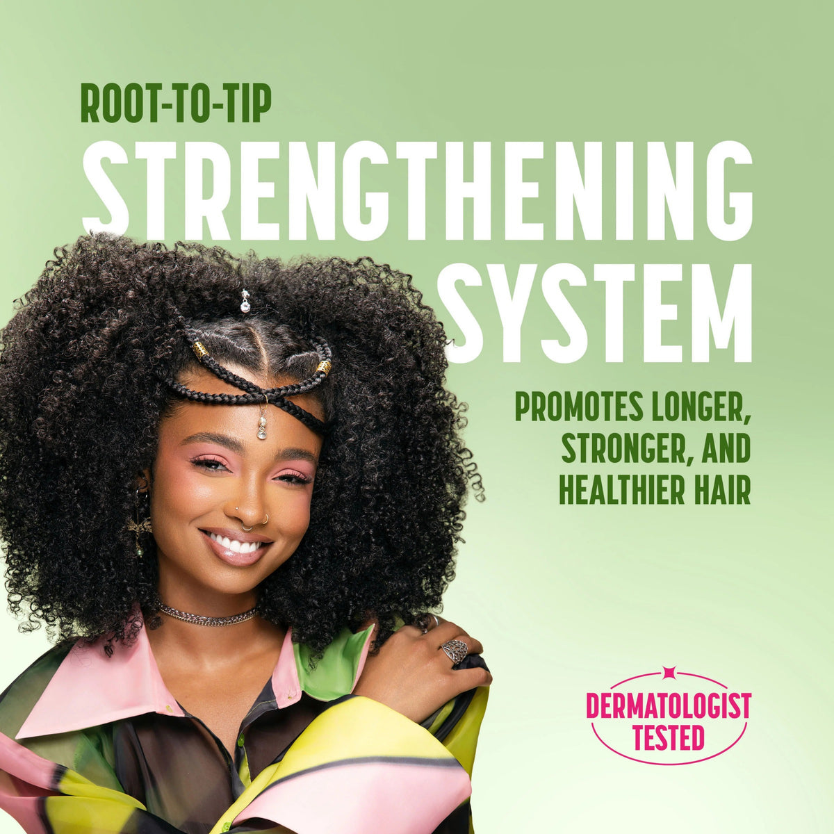 Smilende kvinde med krøllet afro-hår og flettet pandebånd promoverer Root-to-Tip Strengthening System til stærkere, sundere hår.